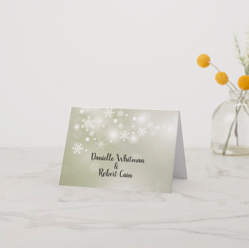 White snowflakes and stars on a beautiful sage green bokeh (blurred lights) background folded thank you notes - matches our winter themed engagement party invitations, birthday invitations and more. Shop PartyInvitationsShop.com